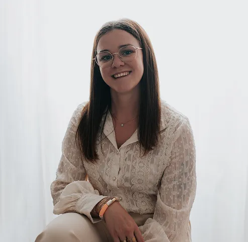 Portrait d’une femme souriante assise près d’une fenêtre.