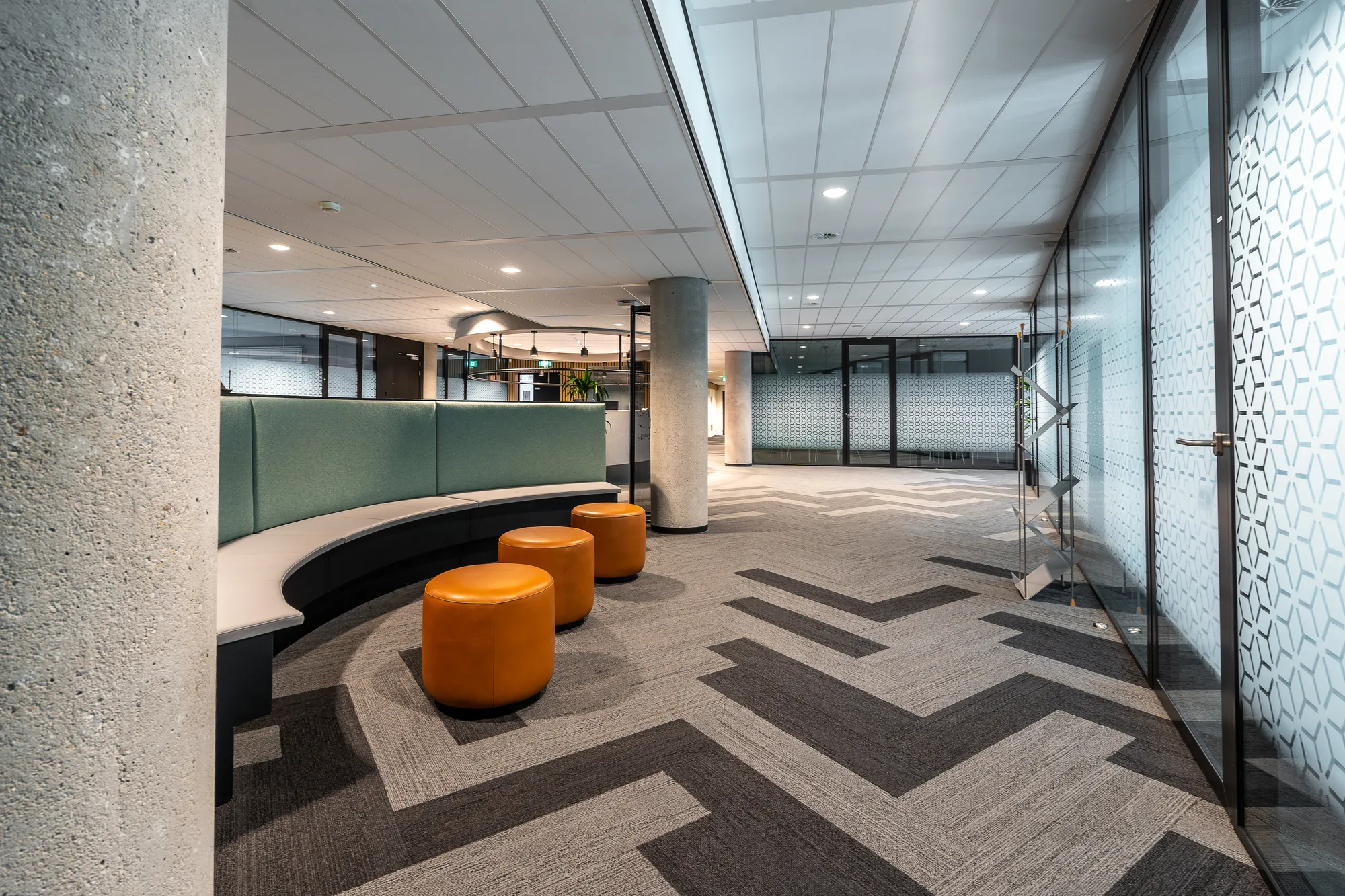 Bureau moderne avec moquette géométrique et sièges orange.